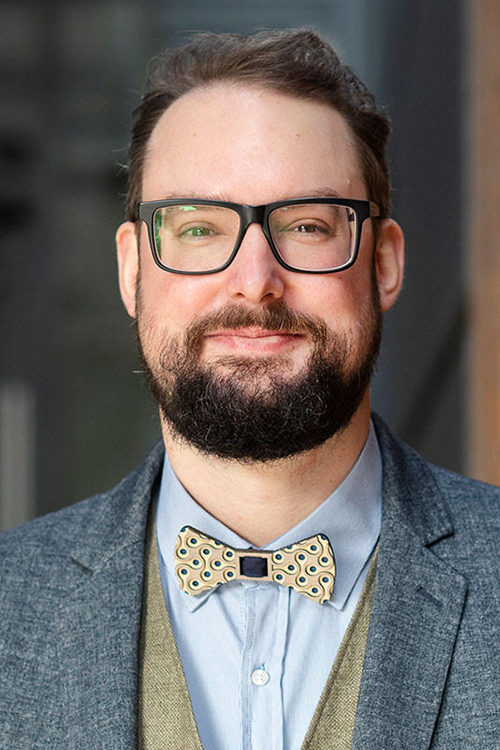 Bearded man with glasses in a suit and bowtie
