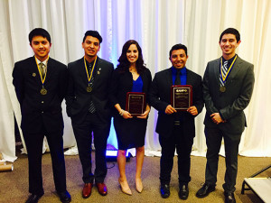 5 people standing in line with two holding plaques