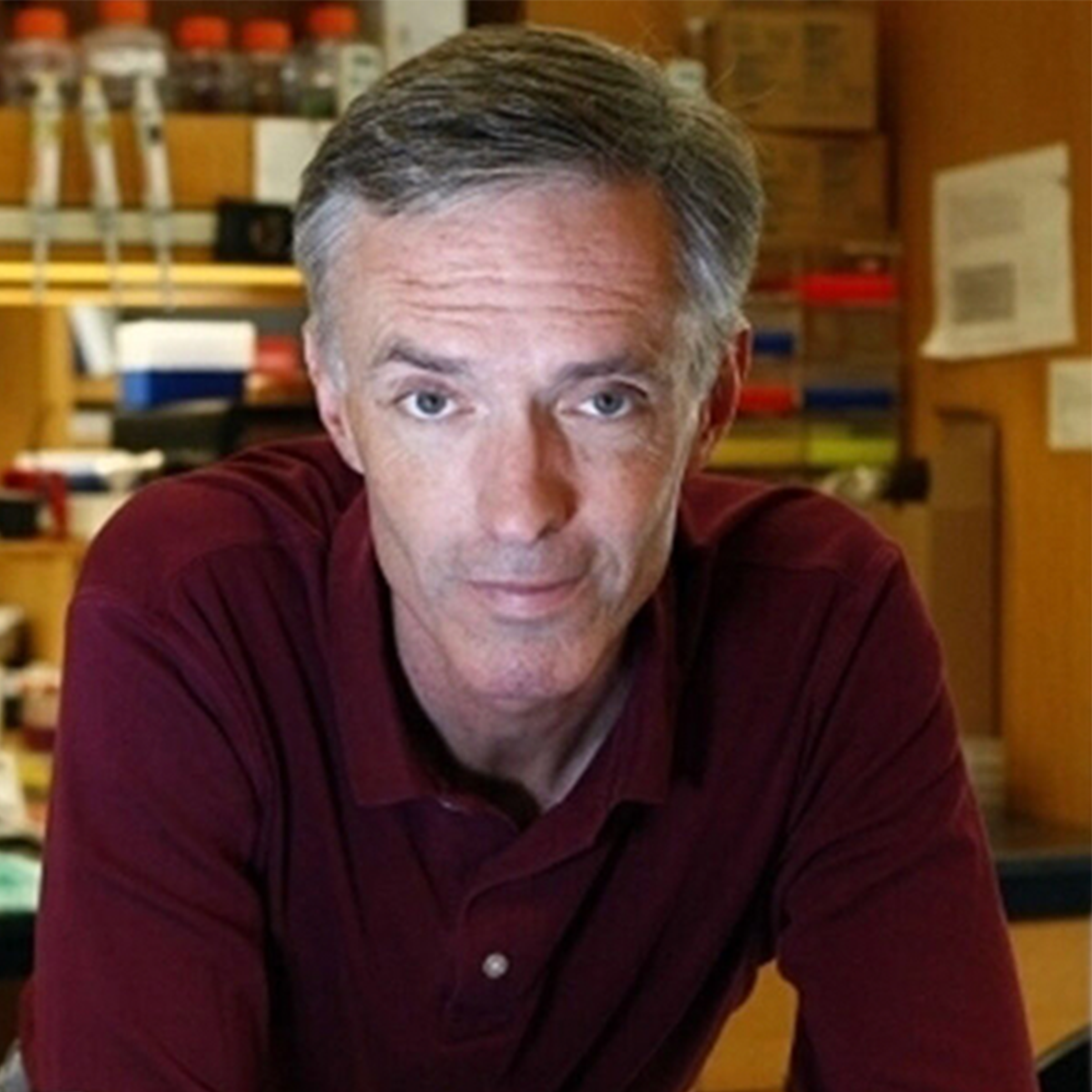 An individual with short hair and a maroon sweater 