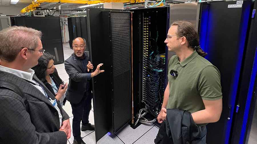 A group of people stands in front of a large black cabinet holding compute nodes.