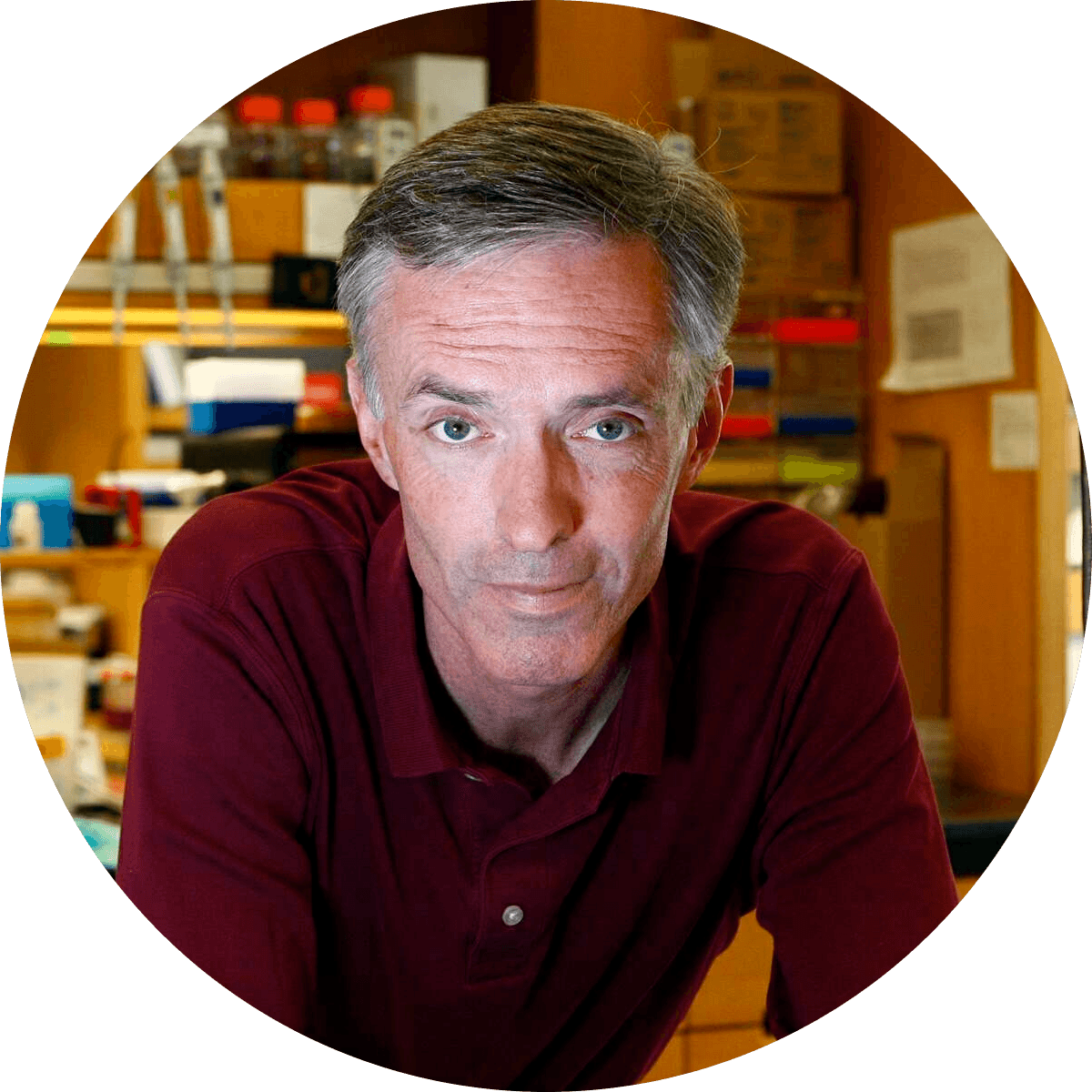 an individual with short graying hair leans toward the camera with a slight smile