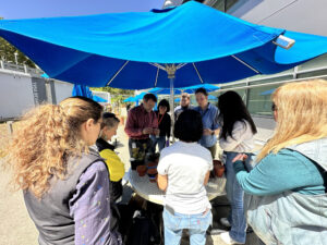 a group of people huddled under an umbrella
