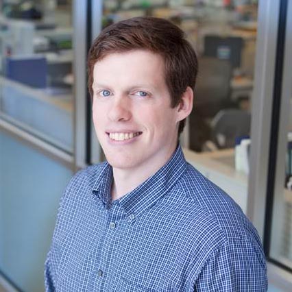 An individual with short hair and a blue checked shirt 