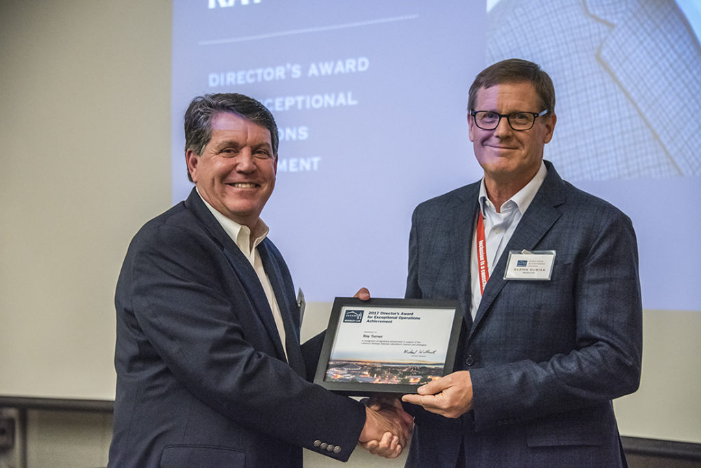 two people holding a framed picture in front of a presentation