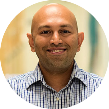 A smiling person in a checkered shirt.