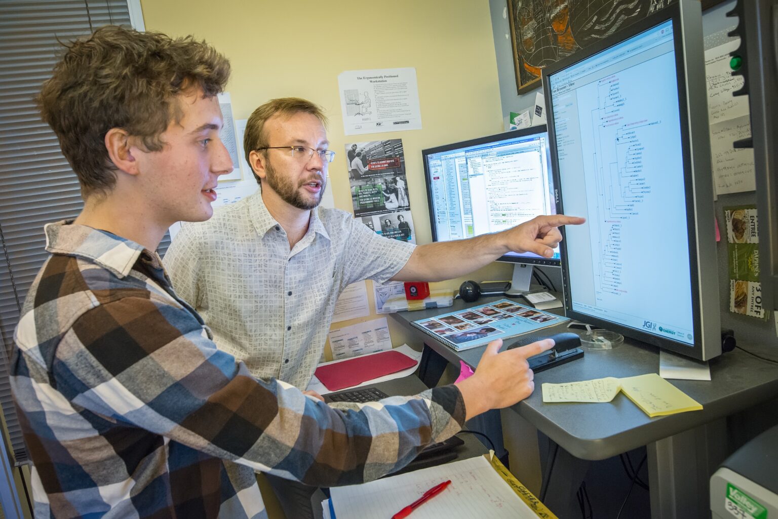 a scientist and intern looking at a computer