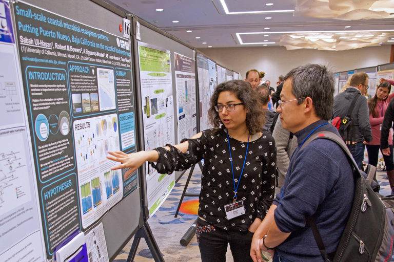 student and mentor discuss scientific poster at conference