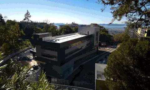 a gif of the integrative genomics building shows a view of the bay in the backdrop as the sky transitions from day to night