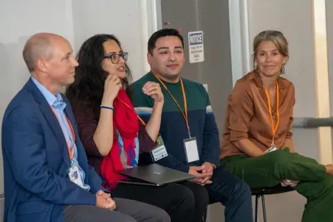 four people sitting in chairs discussing a topic