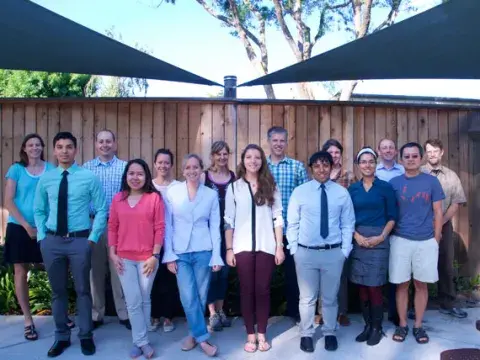 a group shot of people in front of a fence