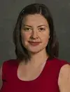 an individual with shoulder-length brown hair smiles at the camera