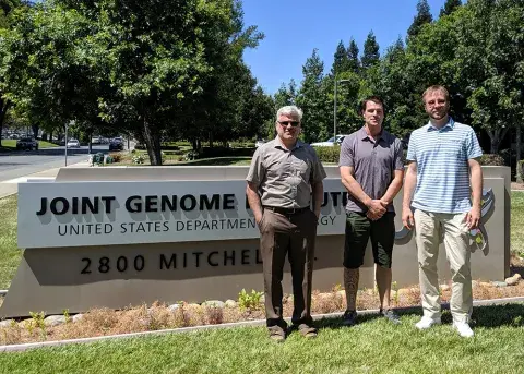 three people standing by a sign