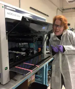 a person with lab gear standing next to a machine