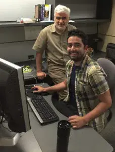 two people at a desk posing for a photo