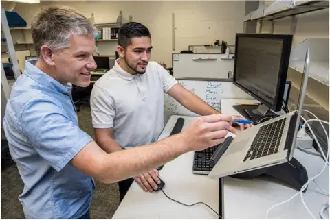 two people looking at a laptop