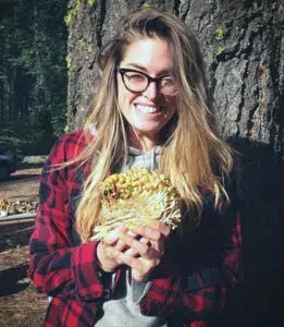 a person standing in front of a tree holding mushrooms