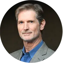 Person in a gray plaid jacket and blue shirt against a dark background