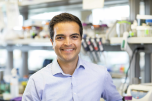 Aaron Puri smiles in front of a lab bench