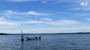A small boat floats to the right of a buoy, named David's Buoy, on Lake Mendota.