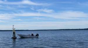 A small boat floats beside a buoy, named David's Buoy, on Lake Mendota.